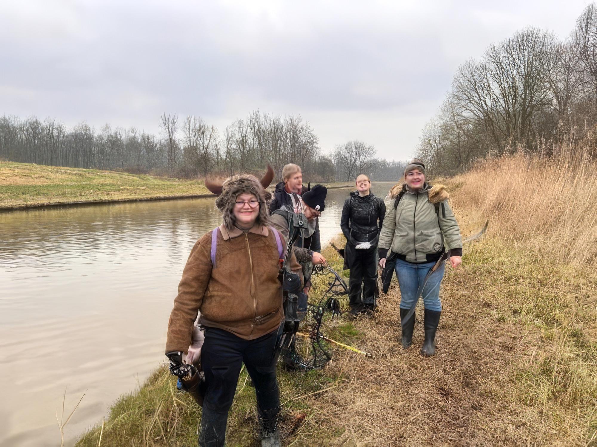 Clubleden met hun bogen langs het water tijdens een buitenactiviteit